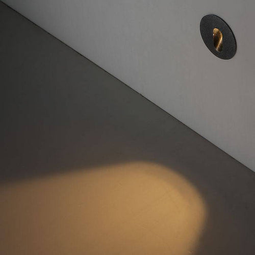 black outdoor stair step light mounted at low level on a white wall