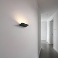 Black internal wall uplighter on a grey wall in a hallway of a modern home