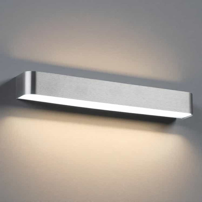 silver up and down interior wall sconce mounted on a grey wall
