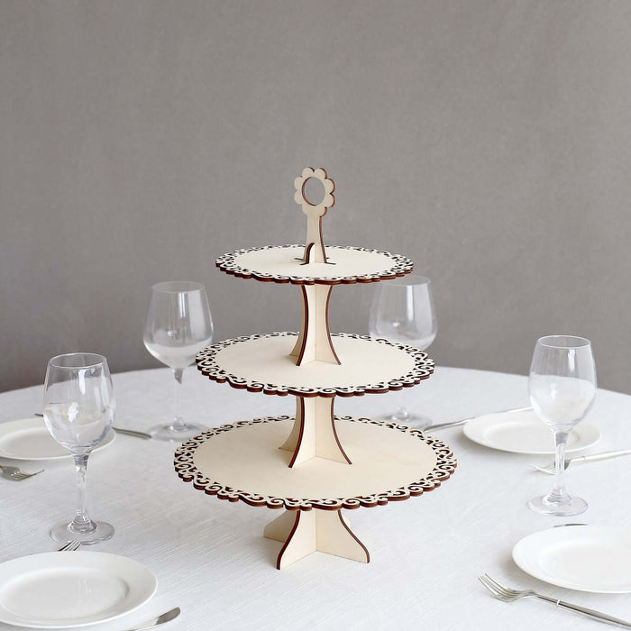 Three-tiered wooden cake stand with decorative edges on a table setting.
