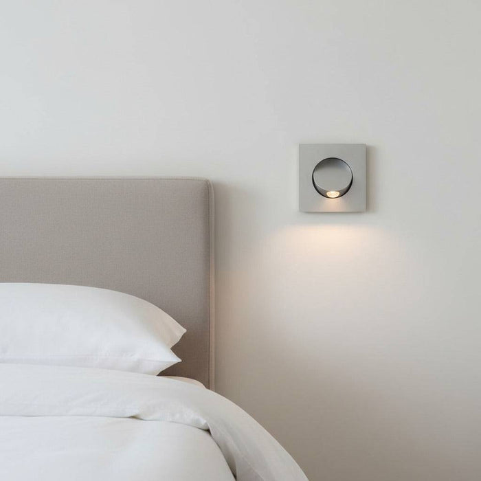 silver recessed wall or headboard reading lamp mounted flush in the wall next to a bed in a modern bedroom