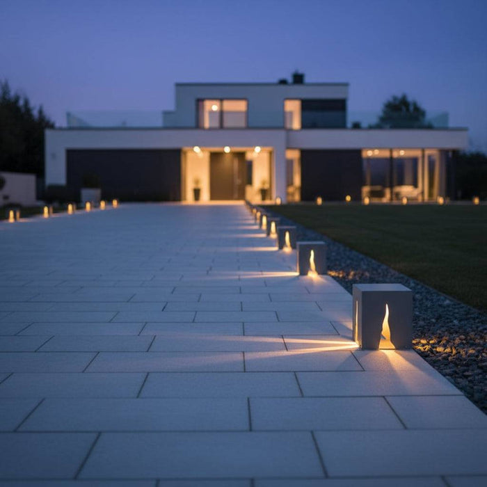 Grey contemporary bollard lights on a paved driveway leading to a modern house