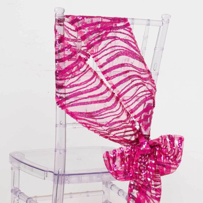 Pink sequined chair sash tied in a bow on a clear chair.