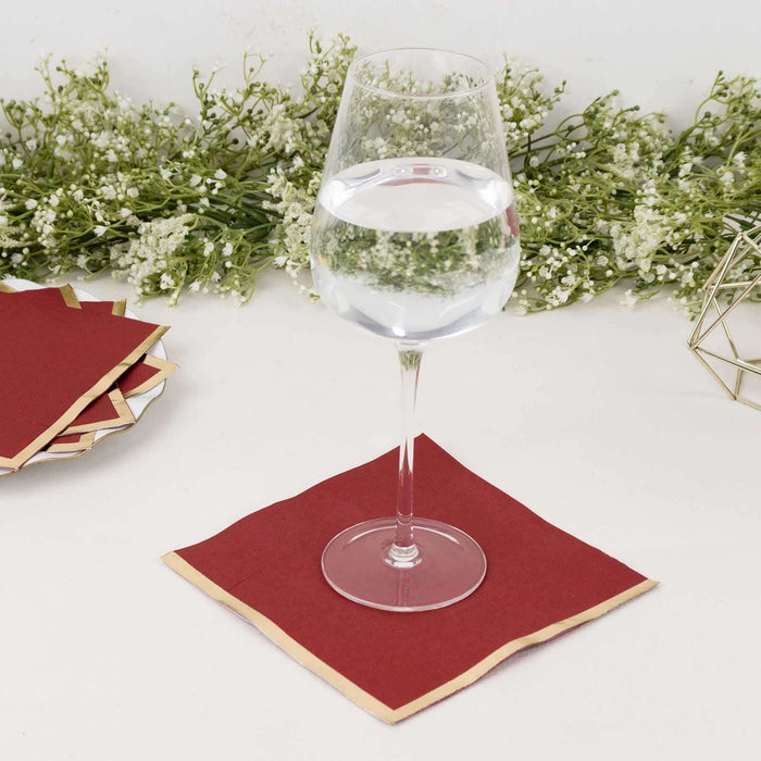 Elegant glass of water on a red napkin with decorative greenery in the background.