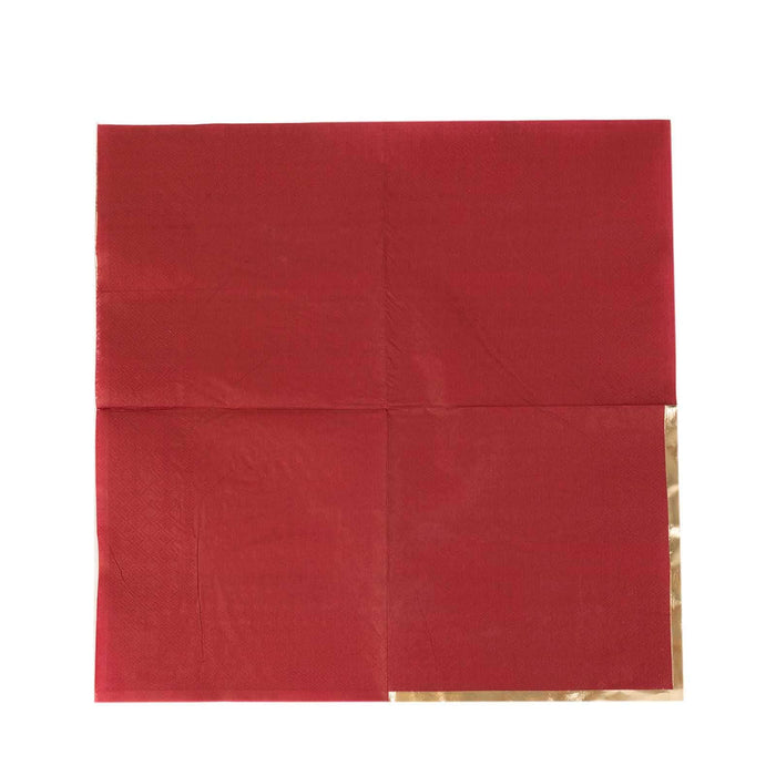 Red napkin with gold trim, folded in quarters.