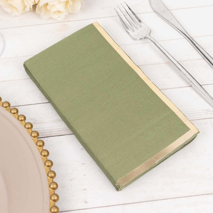 Green napkin with gold trim set on a dining table.
