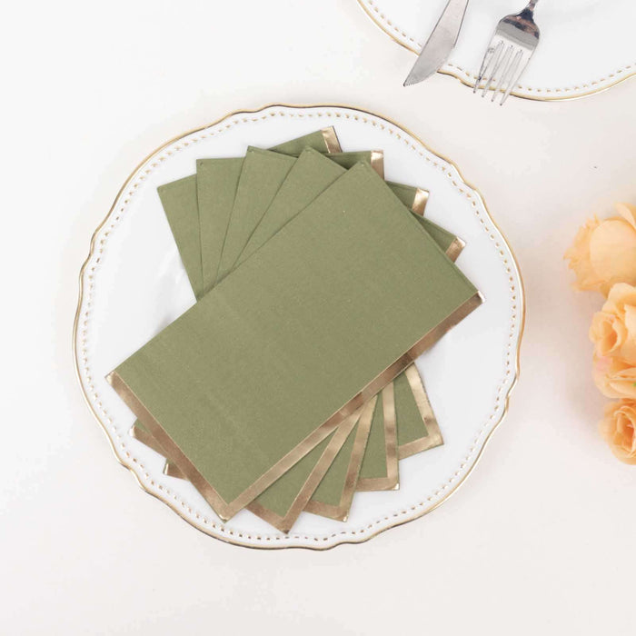 Green napkins with gold trim on a decorative plate.