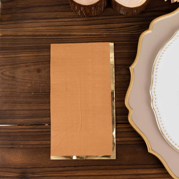 Brown paper napkin with gold foil edge on a wooden table.