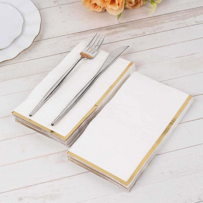 Gold-trimmed napkins with fork and knife on a wooden table.