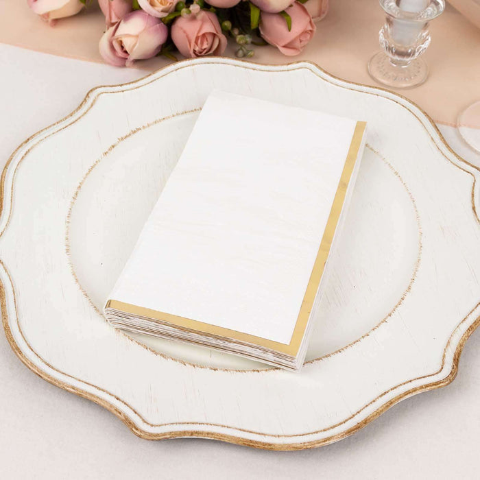 Elegant white napkin with gold trim on a decorative plate.