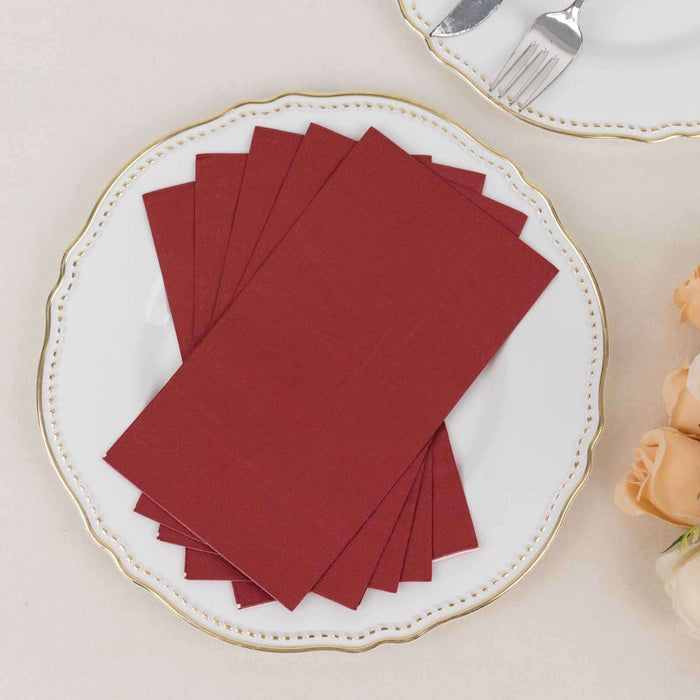 Burgundy napkins stacked on an elegant plate with floral accents.