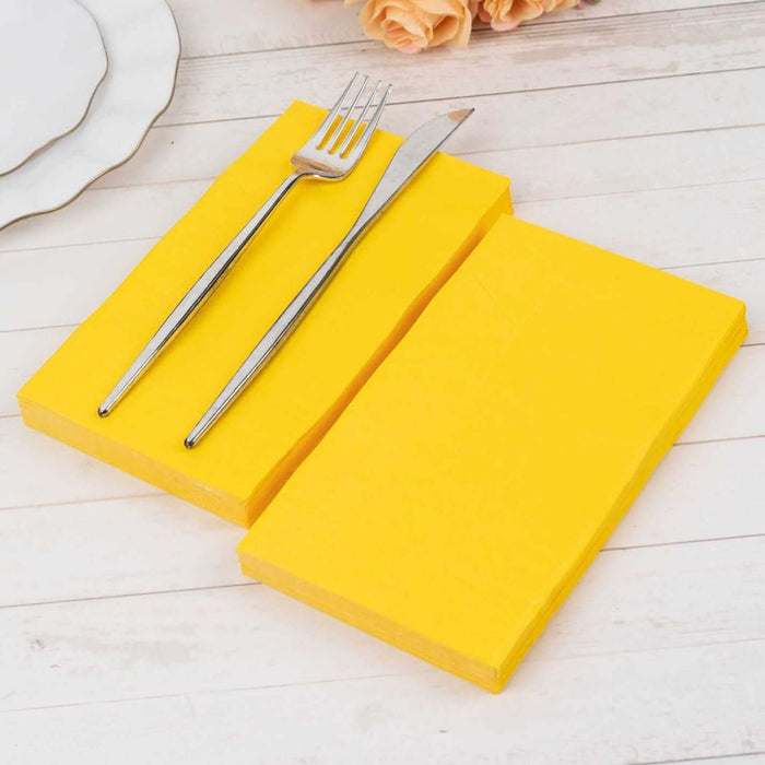 Yellow napkins with a fork and knife on a wooden table.