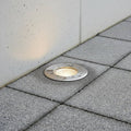 stainless steel outdoor ground lamp mounted in the ground next to a wall