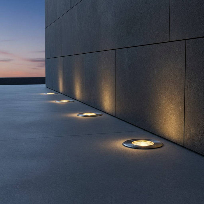 stainless steel outdoor ground lamp mounted in a row next to a wall outside