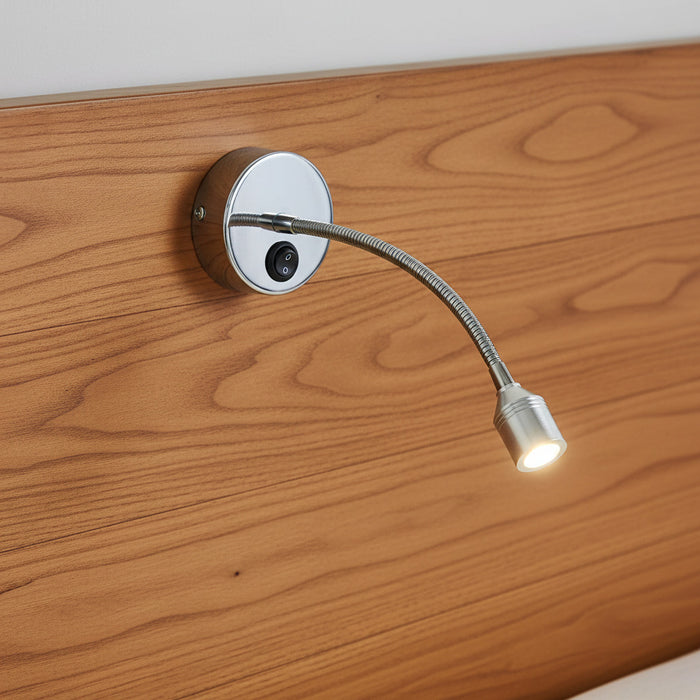 polished chrome flexible reading light mounted on a wooden headboard