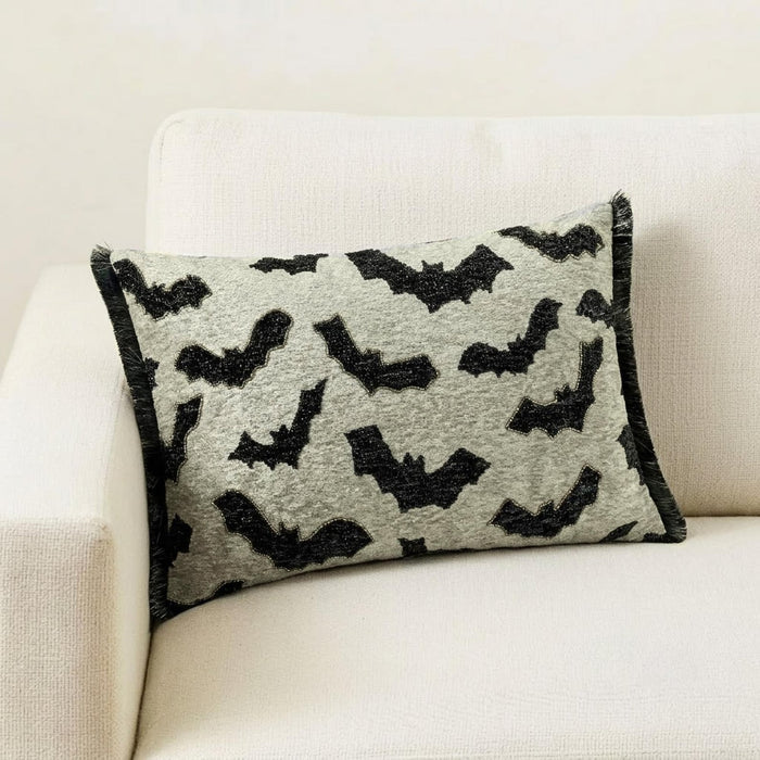 A Halloween-themed display featuring a decorative pillow with a gothic bat pattern on a brown surface surrounded by a card theme frame.