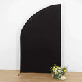 Black curved backdrop with artificial flowers on the floor.