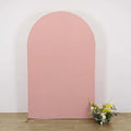 Pink arch backdrop with floral arrangement in front.