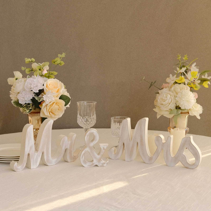 Decorative "Mr & Mrs" wooden letters with floral arrangements on a dining table.