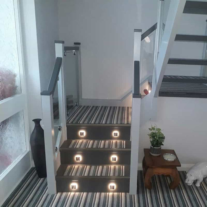 mini interior step light installed on a home stairway with striped carpet
