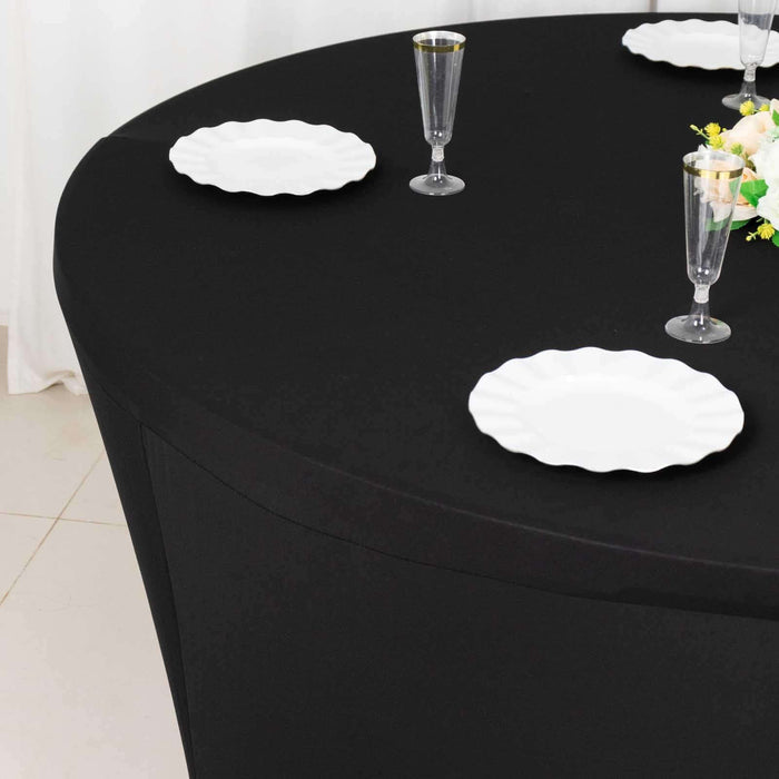 Round black table with white plates and glassware set for dining.