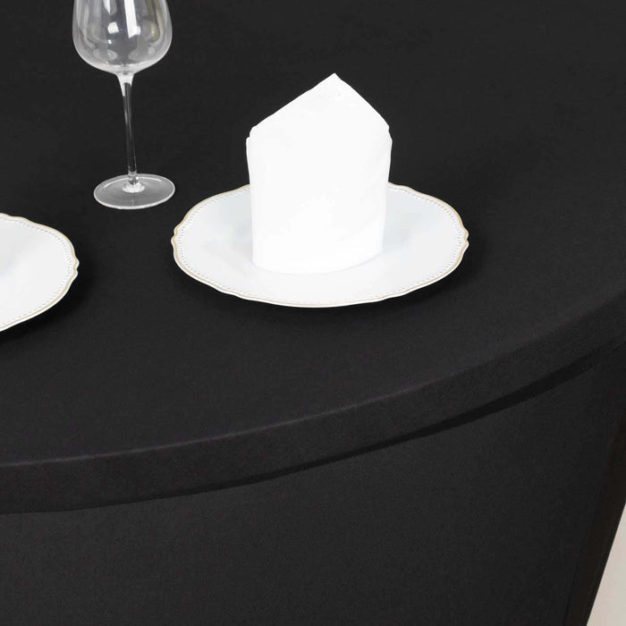 Black tablecloth set with white plates and napkins for elegant dining.