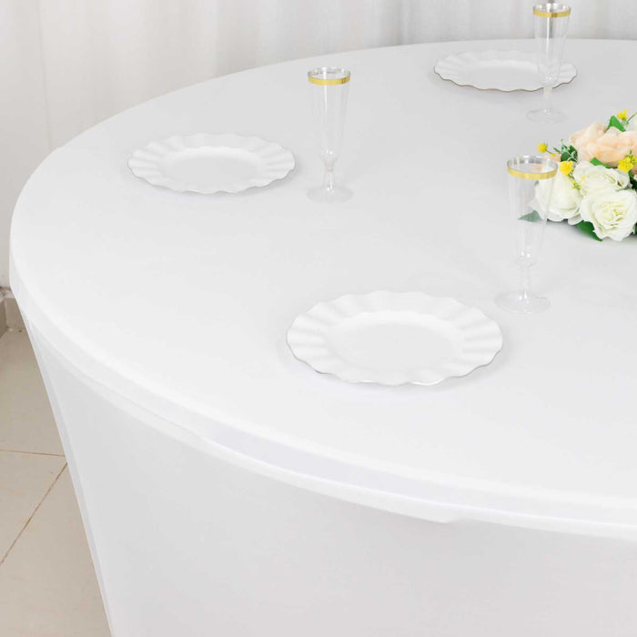 Round table set with white plates and elegant floral centerpiece.