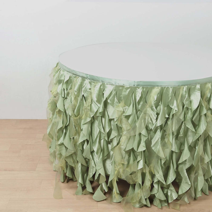 Round table with green ruffled table skirt on a wooden floor.
